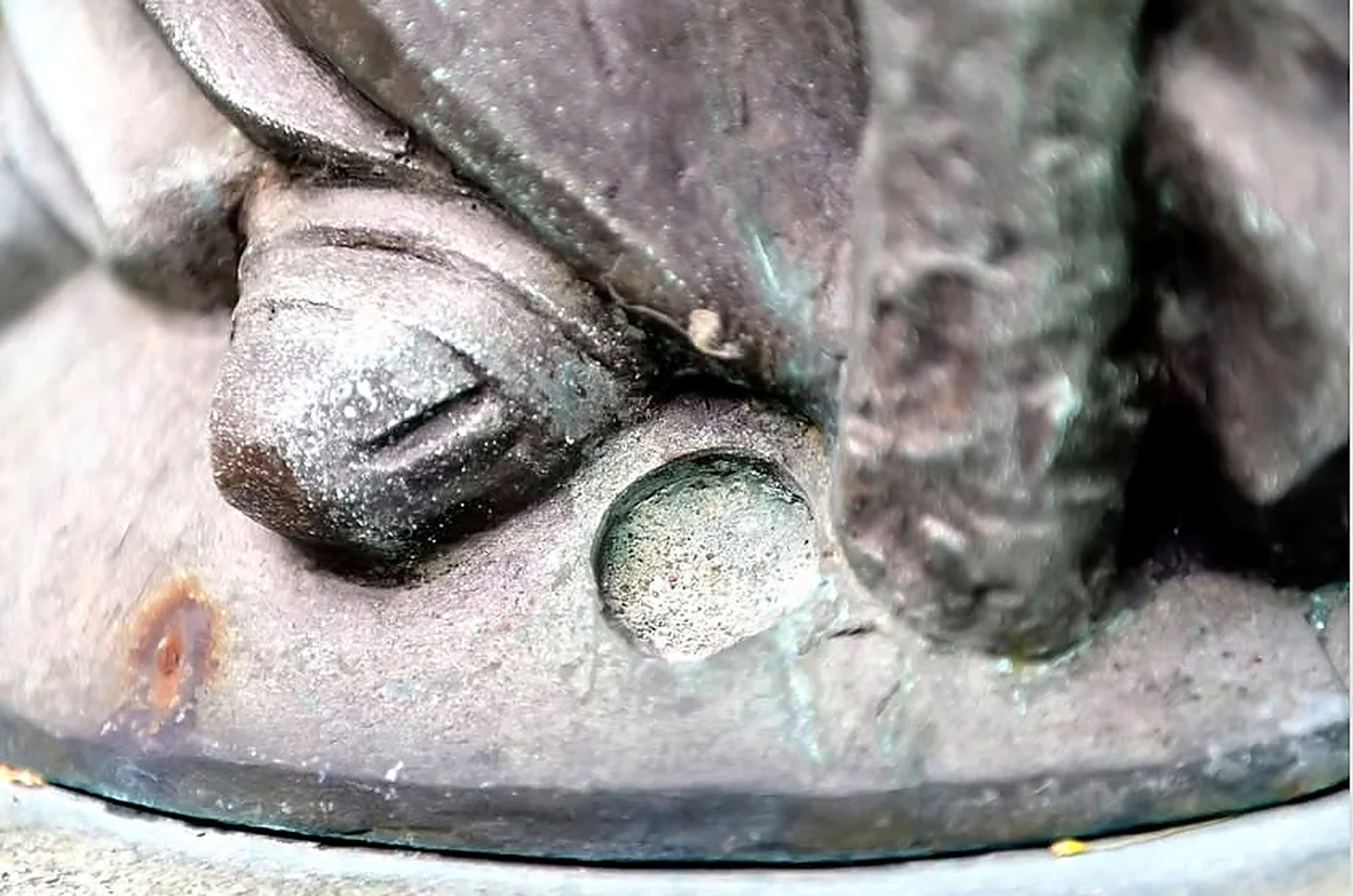 Detalle de un pie de bronce y la base redonda de la estatua