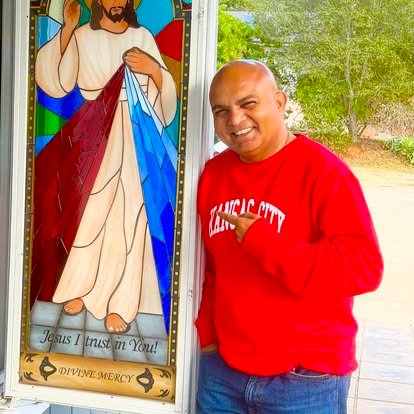 Un membre de la communauté près d’un vitrail de la Divine Miséricorde